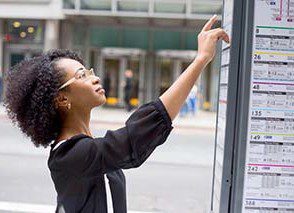 Adult learner using public transport information in a real-world setting as part of ESOL (English for Speakers of Other Languages) learning and everyday communication skills development.