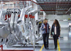 A team leader discussing work activities with a colleague in a manufacturing environment.