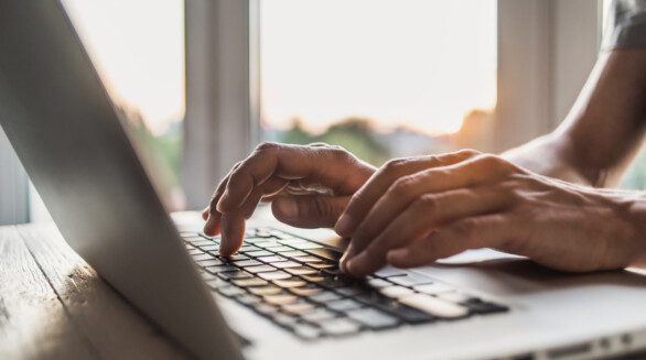 Hands typing on laptop computer keyboard