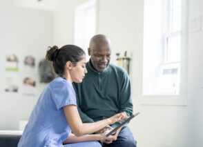 A health care worker speaks to a patient whilst using an iPad.